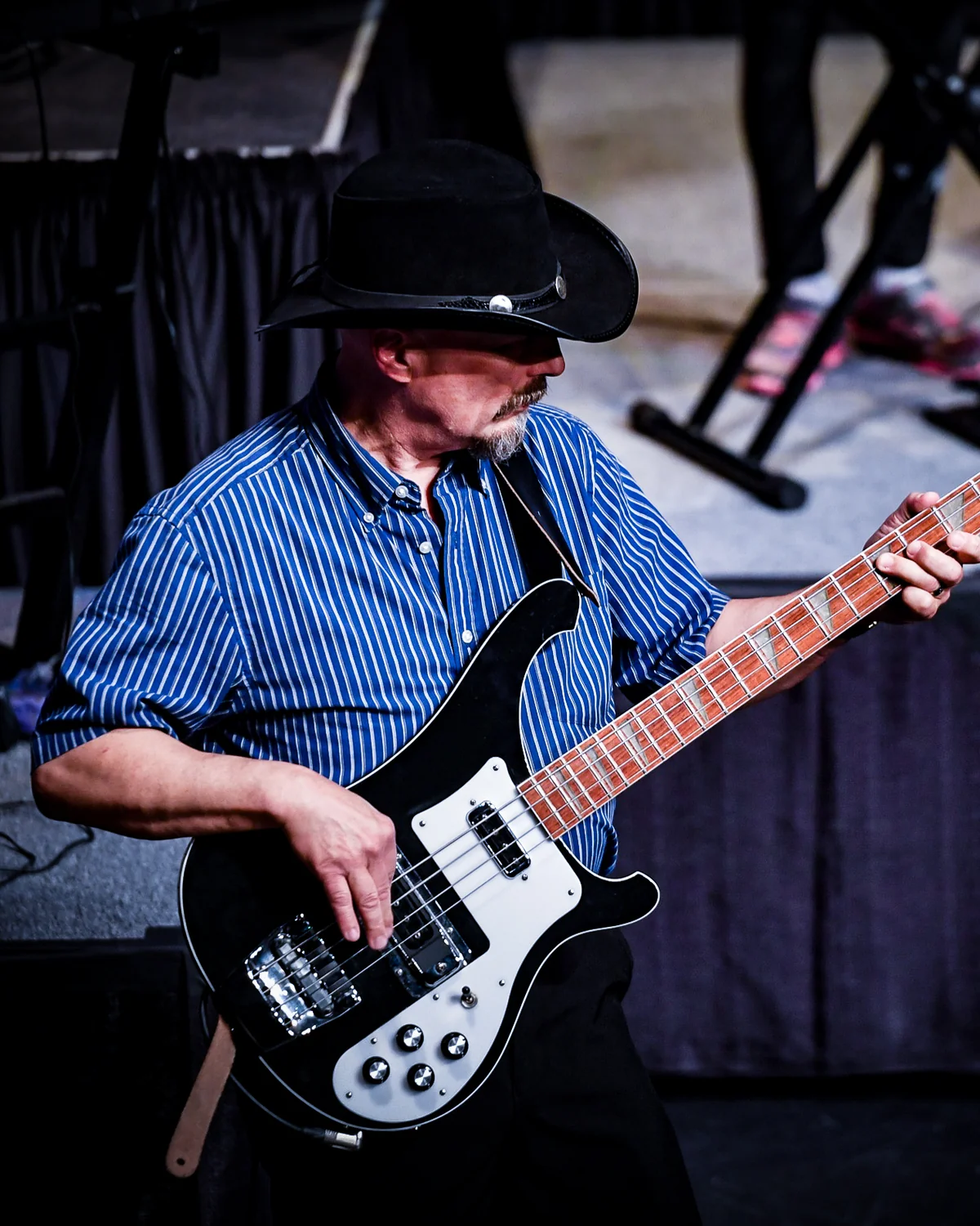 Bass student seated on a stool playing a teal short-scale bass on the Resonate stage in Edmonton